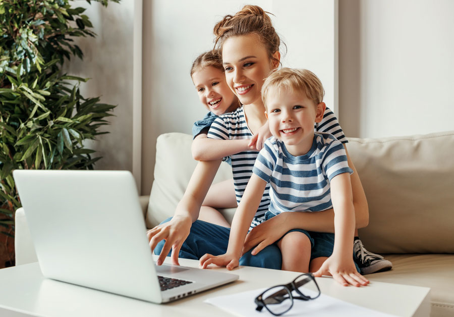 Junge Frau mit Kindern arbeitet am Laptop im Homeoffice